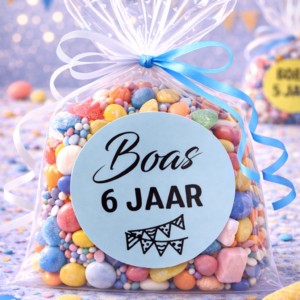 Feestelijk snoepzakje met kleurrijke snoepjes en label 'Boas 6 jaar' met blauw lint