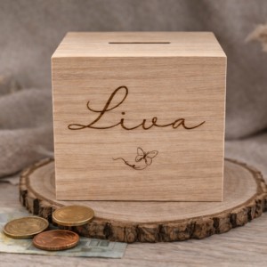 Houten spaarpot met gegraveerde naam Lisa en vlindermotief, geplaatst op boomschijf met munten en bankbiljet