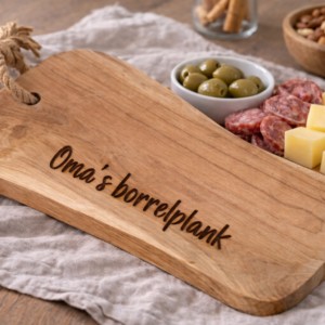 Houten borrelplank met touwhandvat en gravure 'Oma's borrelplank', belegd met kaas, worst en olijven