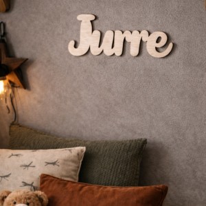Houten letters 'Jurre' als naamdecoraie op grijze muur boven bed met knuffelbeertje en kussens in cadeauwinkel