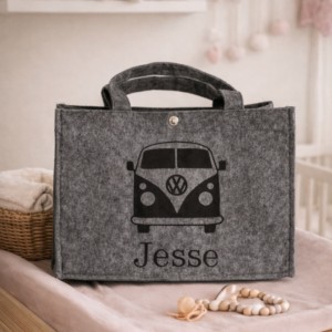 Grijze vilten tas met Volkswagen bus opdruk en gepersonaliseerde naam Jesse op houten bankje in kinderkamer