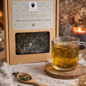 Groene thee cadeauverpakking met mango en rabarber van ARELO, geserveerd in glazen theekop met kaarslicht