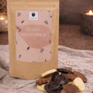 Arelo zakje met luxe chocoladestukjes in wit, melk en puur met sfeerverlichting op de achtergrond