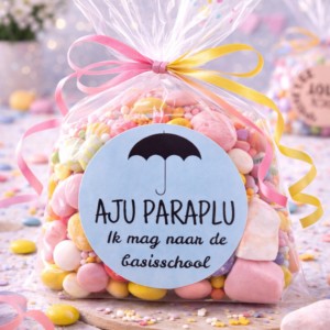 Kleurrijk snoepzakje met roze en gele strikken en label 'Aju paraplu ik mag naar de basisschool